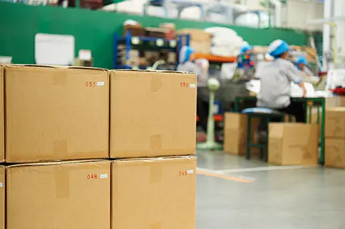 Factory interior with boxes in the foreground and workers in the background